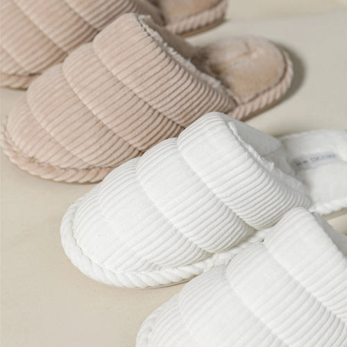 Pair of white and khaki corduroy slippers on a light background