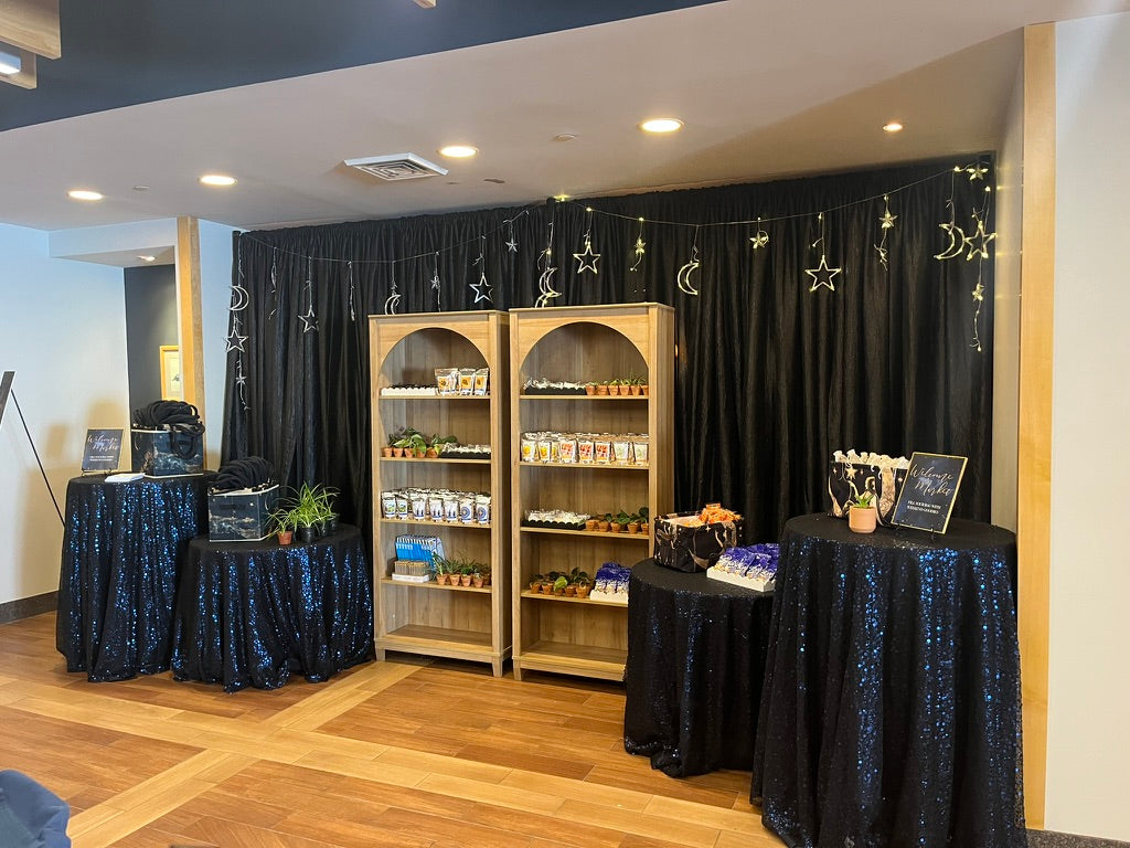 Custom designed welcome market with modern arch shelves and midnight sky table linens featuring local Northern Michigan goods such as Great Lakes Tea & Spice, Grocer's Daughter Chocolate, and hangover emergency kits.